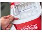 Ręka nabiera kostki lodu z czerwonej maszynki do lodu Coca-Cola.