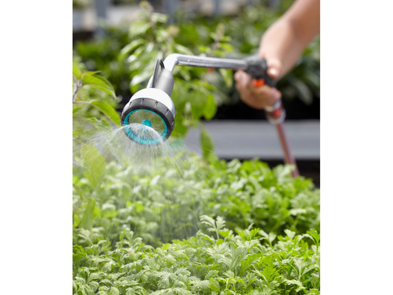 Zraszacz ogrodowy podlewa rośliny wodą.