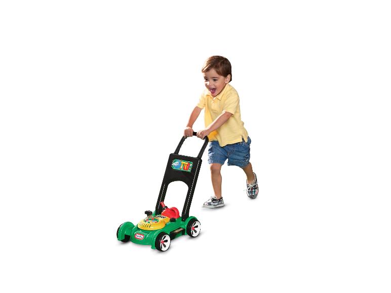 Szczęśliwy chłopiec bawi się zieloną zabawką kosiarką Little Tikes.