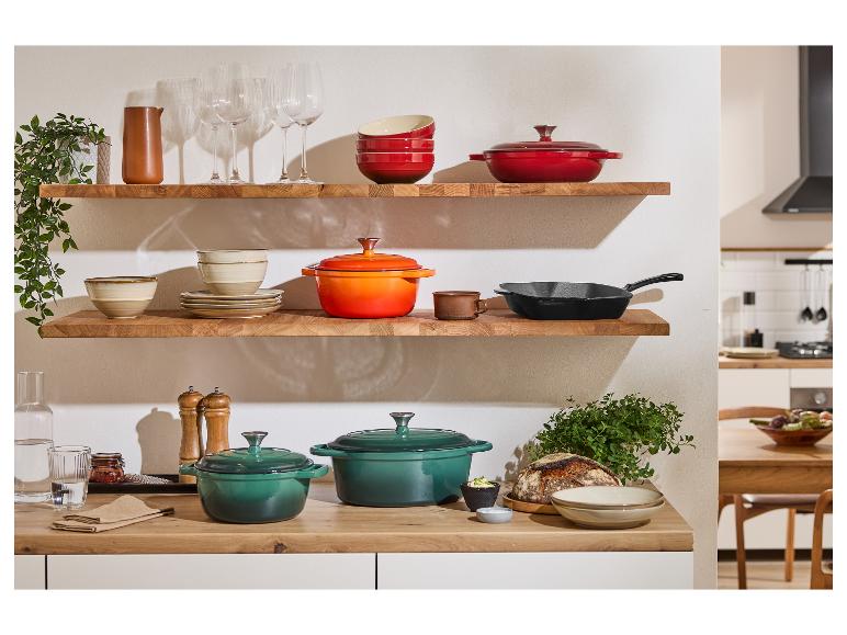 Stylowa kuchnia z żeliwnymi garnkami Le Creuset w kolorach zielonym, pomarańczowym i czerwonym.