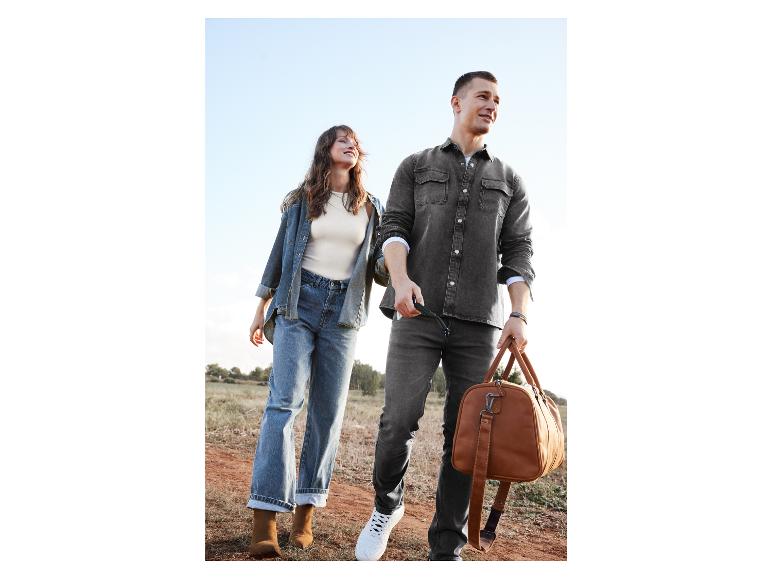 Para idzie z skórzaną torbą podróżną i dżinsowymi ubraniami.