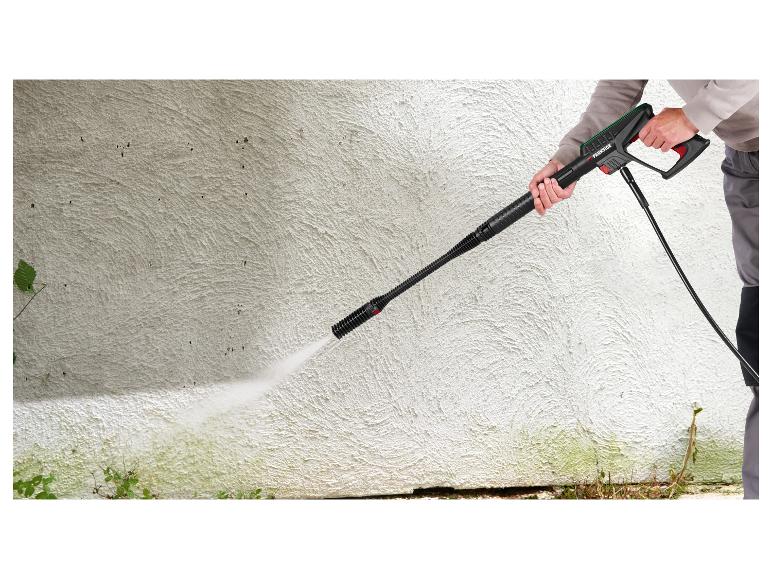 Osoba czyści teksturowaną ścianę myjką ciśnieniową PARKSIDE.
