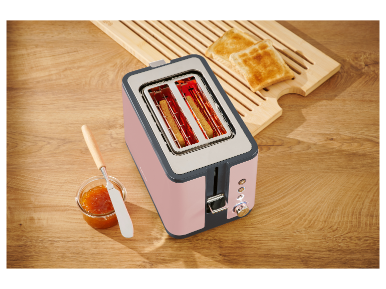 Różowy toster dwuprzegrodowy z grzankami na drewnianej desce.