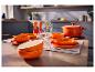 Pomarańczowy 16-częściowy serwis obiadowy SILVERCREST® nakryty na stole.