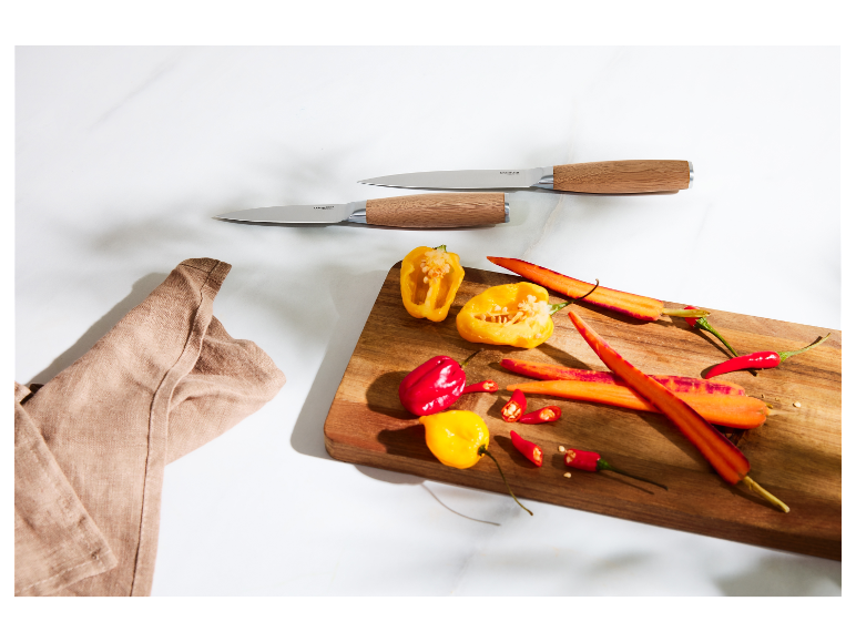 Noże kuchenne SilverCrest i pokrojone warzywa na drewnianej desce.