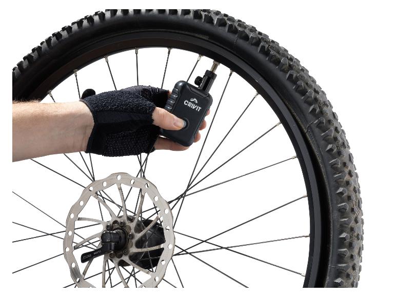 Ręka w rękawiczce pompuje oponę rowerową Crivit cyfrową pompką powietrza.