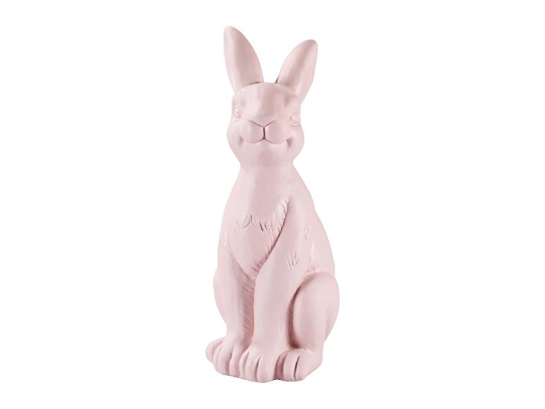 Jasnoróżowy ceramiczny siedzący królik dekoracyjny na Wielkanoc.