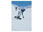 Snowboardzista w spodniach we wzory i jasnoniebieskiej kurtce zjeżdżający po śnieżnym stoku.