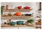 Stylowa kuchnia z żeliwnymi garnkami Le Creuset w kolorach zielonym, pomarańczowym i czerwonym.
