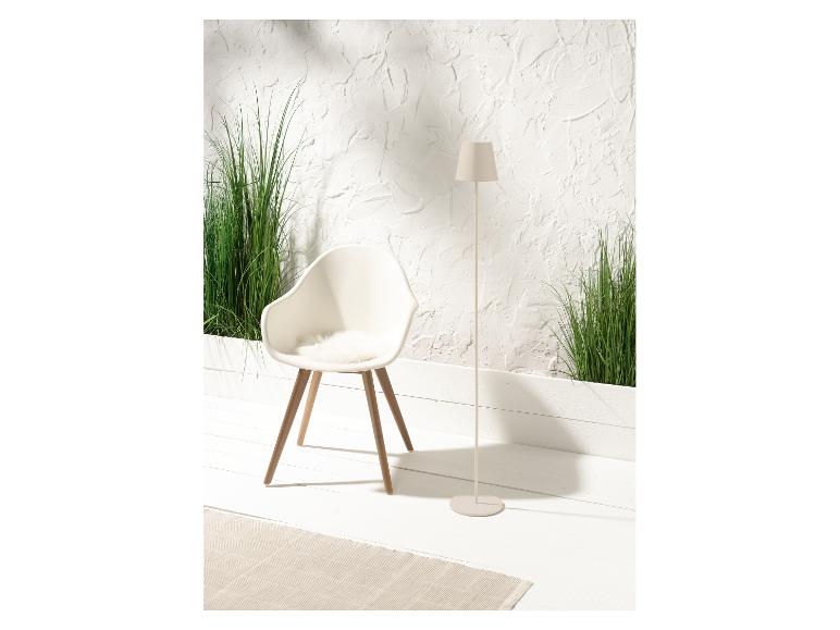 Białe designerskie krzesło, lampa podłogowa i zielone rośliny w minimalistycznym wnętrzu.