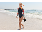 Kobieta w koszulce z długim rękawem, majtkach bikini i masce do snorkelingu idzie po plaży.