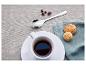 Kawa espresso w białej filiżance z ciasteczkami i ziarnami kawy na lnianym obrusie.