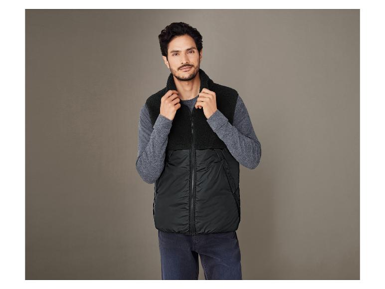 Mężczyzna w czarnej, futrzaną kamizelce z kapturem.