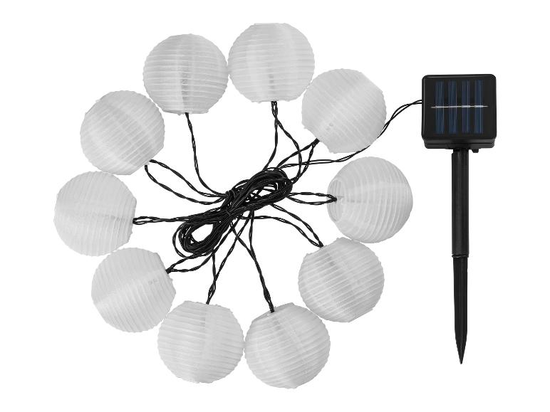 Lampki solarne z dziesięcioma białymi papierowymi lampionami i panelem słonecznym na szpikulcu.
