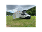Volkswagen Transporter z markizą i namiotem na kempingu.