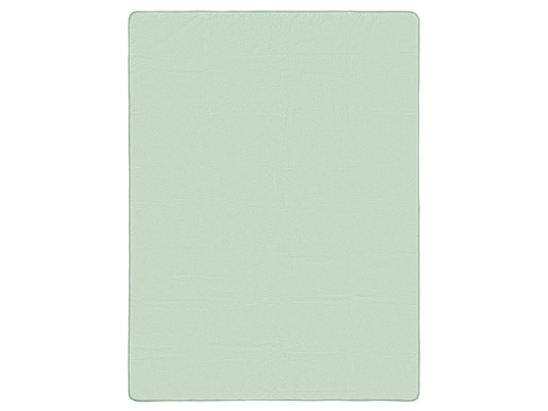 Jasnozielony dywan z geometrycznym wzorem.