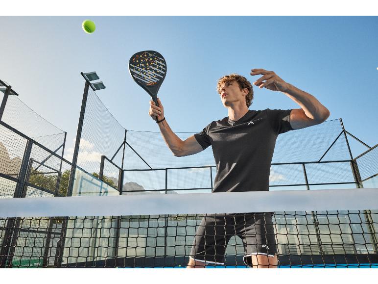 Mężczyzna grający w padla, trzymający rakietę do padla, z piłką tenisową w powietrzu.