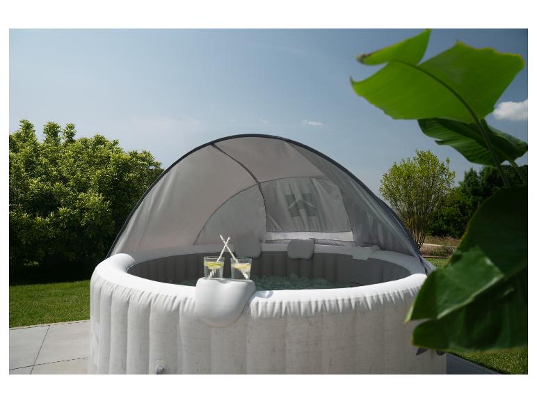 Dmuchane jacuzzi z zadaszeniem, dwoma napojami i zielonym ogrodem w tle.