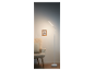 Nowoczesna biała lampa podłogowa LED obok fotela.