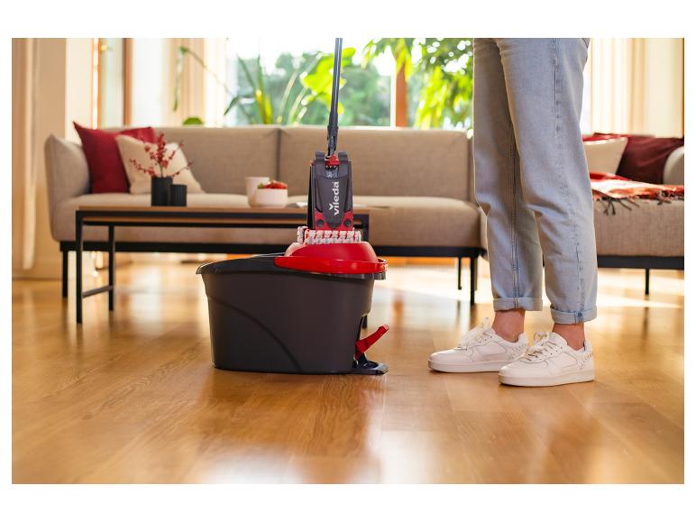 Osoba używająca mopa i wiadra Vileda do czyszczenia drewnianej podłogi w salonie.