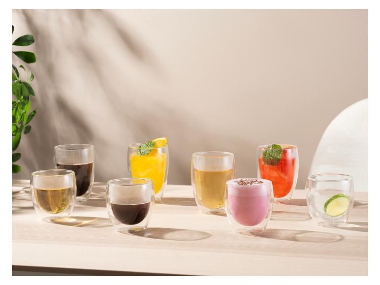 Różne napoje w szklankach z podwójnymi ściankami na drewnianym stole w naturalnym świetle.