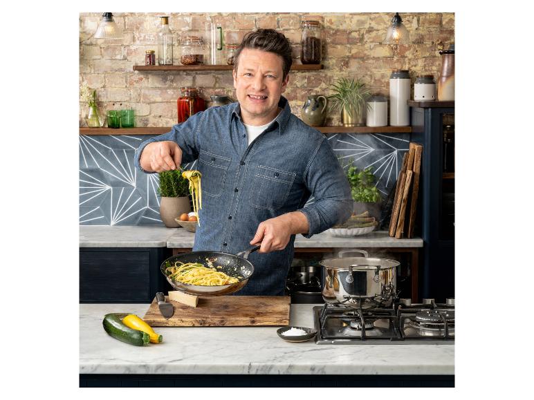 Jamie Oliver gotuje makaron w kuchni z ceglanymi ścianami i marmurowymi blatami.
