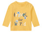 Żółty t-shirt z długim rękawem z napisem 'Travel the World' i obrazkami znaczków pocztowych.