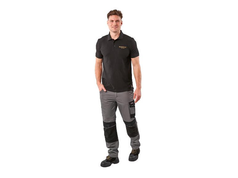 Mężczyzna w czarnej koszulce polo i szarych spodniach roboczych.