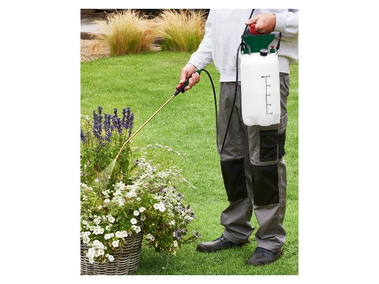 Osoba spryskująca rośliny w ogrodzie opryskiwaczem ciśnieniowym naramiennym.