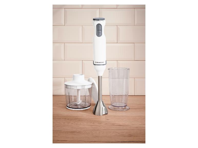Biały blender ręczny z przystawką do siekania i miarką na drewnianej powierzchni.