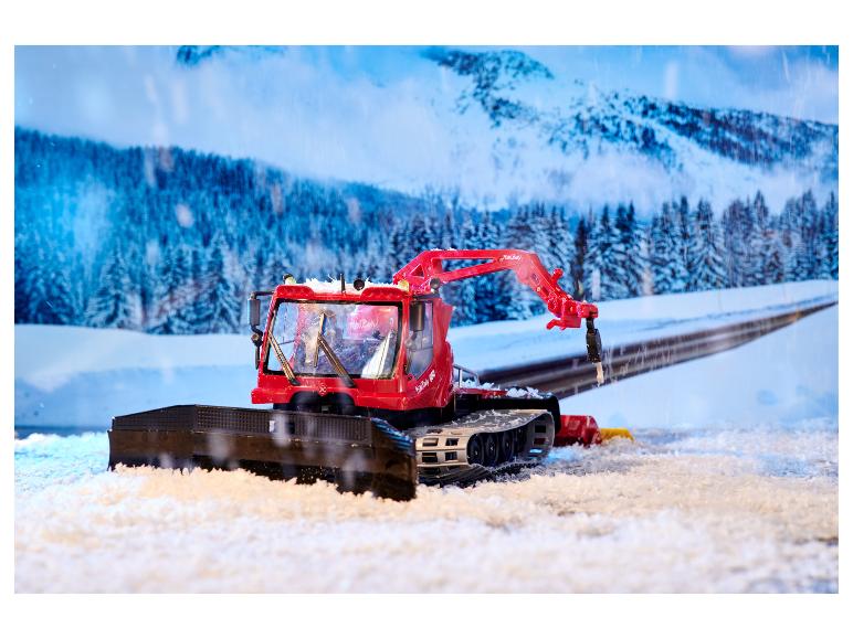 Czerwony ratrak PistenBully 600 z pługiem śnieżnym w zimowym krajobrazie.