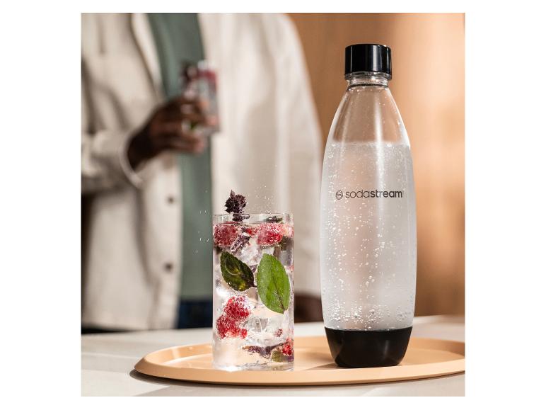 Butelka SodaStream i szklanka napoju gazowanego z jagodami i miętą.