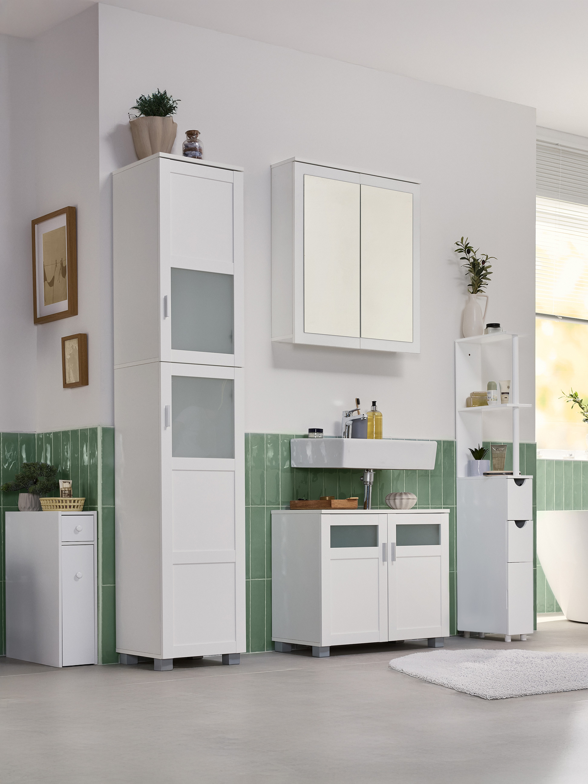 Łazienka z białymi szafkami, umywalką i zielonymi płytkami ściennymi.