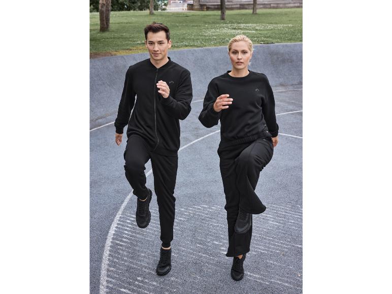 Mężczyzna i kobieta w czarnych dresach i butach Reebok, ćwiczą na zewnątrz.
