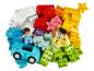 Stos kolorowych klocków LEGO DUPLO z dwiema figurkami i samochodem.