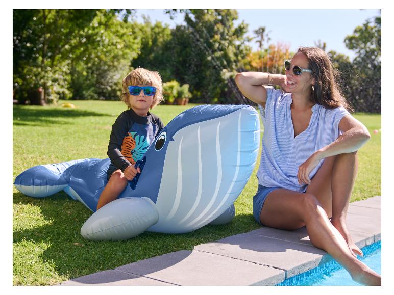 Dziecko bawi się na dmuchanej wielorybie przy basenie.