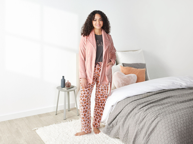 Kobieta w różowej piżamie w serduszka i różowej szlafroku.