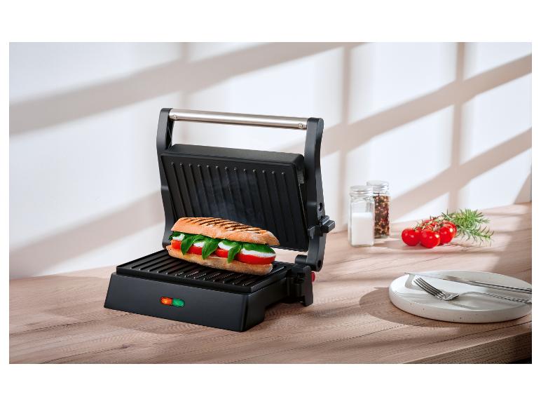 Otwarty opiekacz do panini z kanapką Caprese na drewnianym blacie.