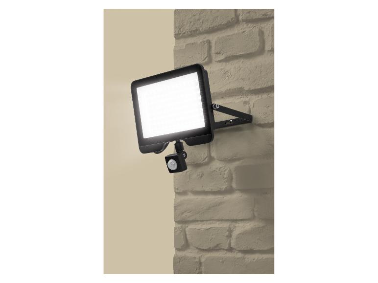 Lampa zewnętrzna LED z czujnikiem ruchu na beżowej ścianie z cegły.