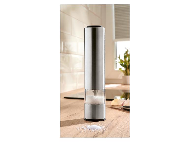 Elektryczny młynek do soli ze stali nierdzewnej na drewnianym blacie kuchennym.