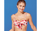Kobieta w białym bikini z czerwonym kwiatowym wzorem.