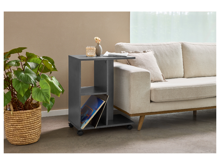 Nowoczesny stolik pomocniczy na kółkach obok beżowej sofy.