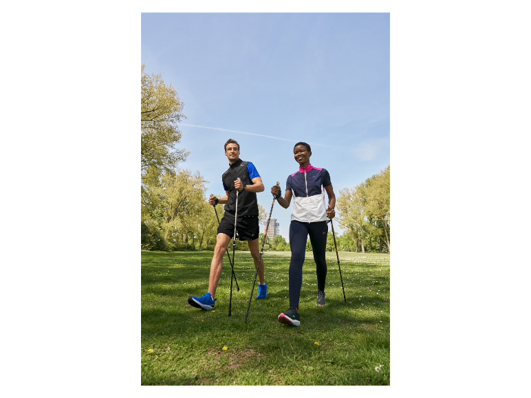 Dwie osoby idą po parku z kijkami do nordic walking.