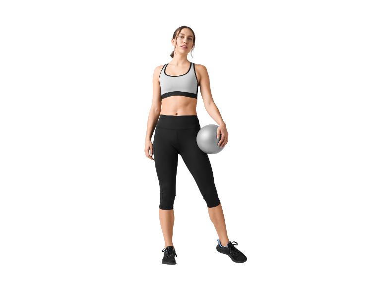 Atrakcyjna kobieta w stroju sportowym z piłką do pilatesu.