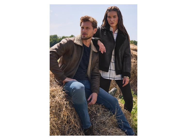 Dwoje modeli w brązowych i czarnych kurtkach z kożuszka pozuje na polu siana.