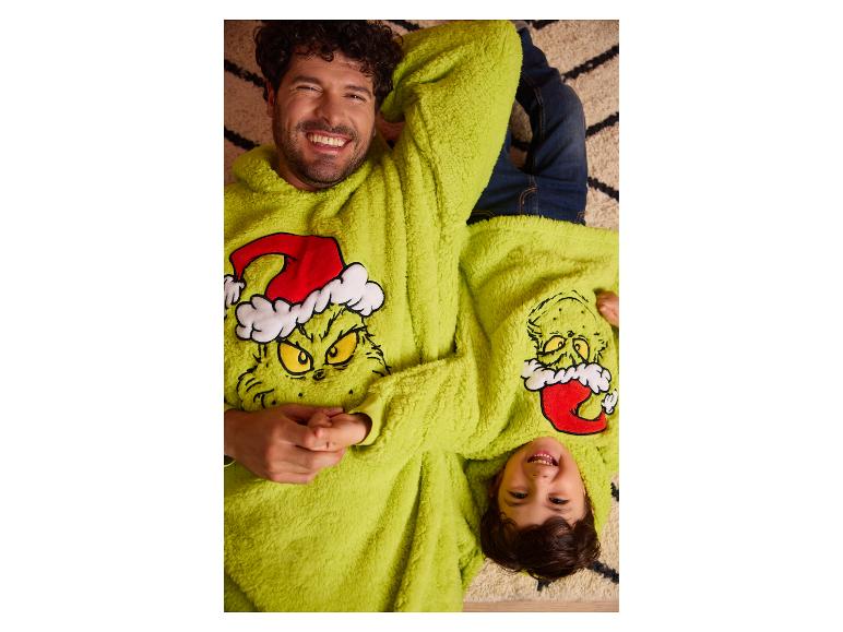 Uśmiechnięci ojciec i syn w pasujących puszystych bluzach Grinch