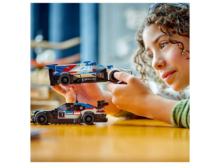 Dziecko bawi się dwoma samochodami wyścigowymi LEGO, w tym BMW M Motorsport.