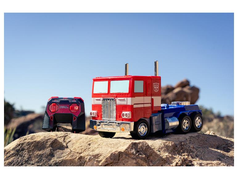 Zabawkowa ciężarówka Optimus Prime i pilot na skalistym terenie pod czystym niebem.