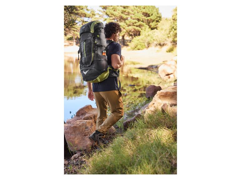 Mężczyzna w butach trekkingowych z plecakiem Quechua nad jeziorem.