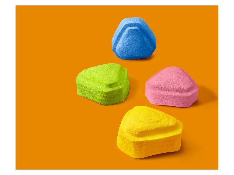 Cztery kolorowe trójkątne gąbki do makijażu na pomarańczowym tle.